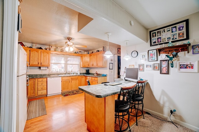 kitchen featuring white appliances, a breakfast bar area, decorative light fixtures, kitchen peninsula, and light wood-type flooring