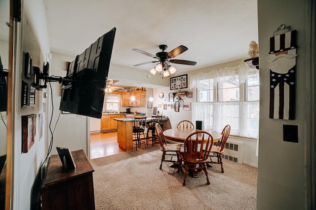 dining area with radiator heating unit, light colored carpet, and ceiling fan