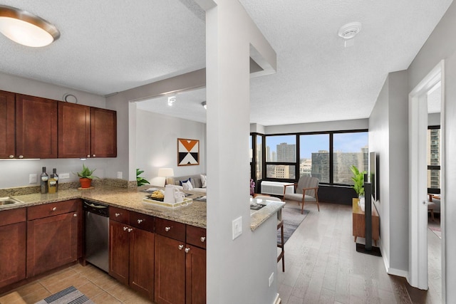 kitchen featuring a textured ceiling, light stone countertops, kitchen peninsula, and dishwasher