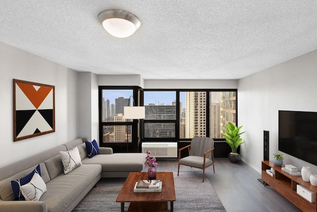 living room with dark hardwood / wood-style flooring, an AC wall unit, and a textured ceiling