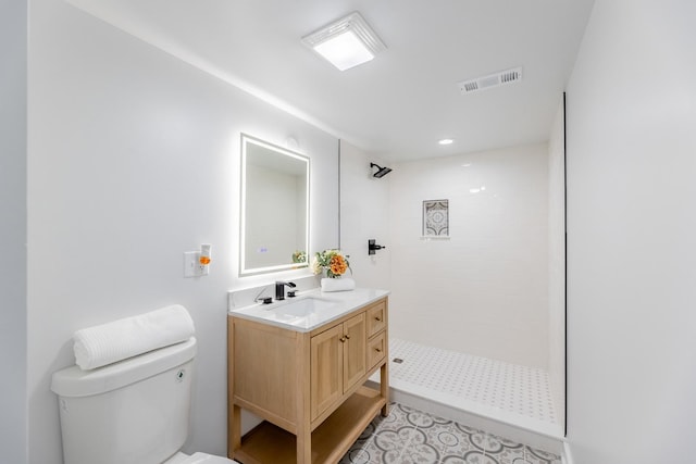 bathroom featuring vanity, toilet, and a tile shower