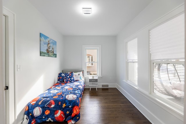 bedroom with multiple windows and dark hardwood / wood-style floors