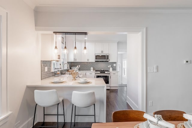 kitchen featuring stainless steel appliances, white cabinetry, backsplash, and decorative light fixtures