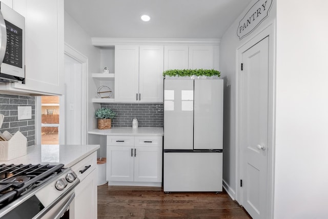 kitchen with white refrigerator, dark hardwood / wood-style flooring, white cabinets, light stone countertops, and backsplash