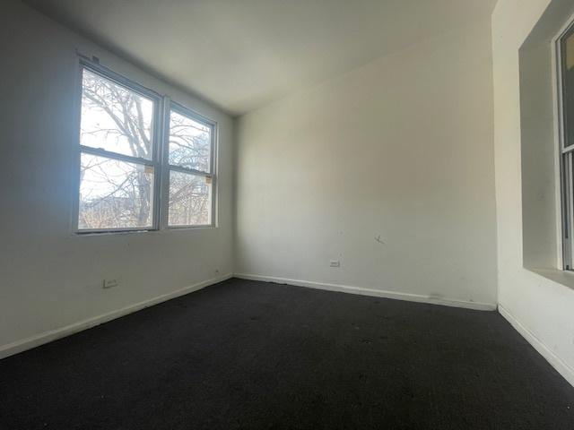 unfurnished room featuring lofted ceiling and dark colored carpet