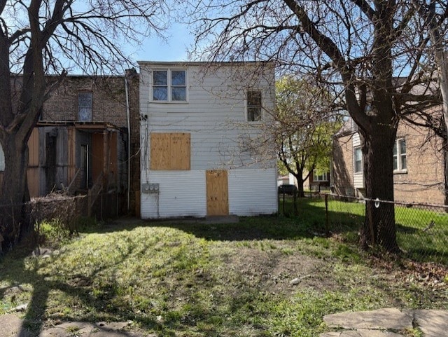 back of property with a lawn and fence