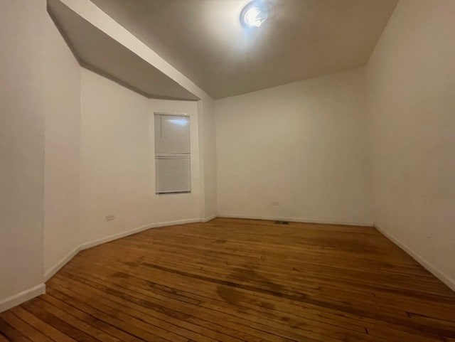 unfurnished room featuring dark hardwood / wood-style flooring and lofted ceiling