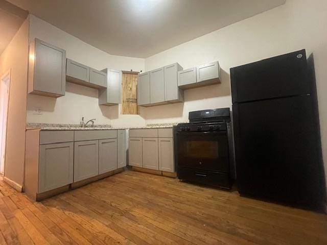 kitchen featuring gray cabinets, sink, light wood-type flooring, and black appliances