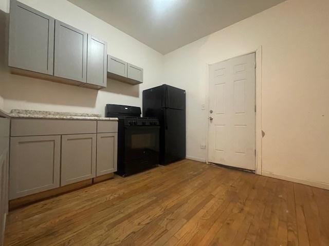 kitchen with gray cabinets, black appliances, and light hardwood / wood-style floors