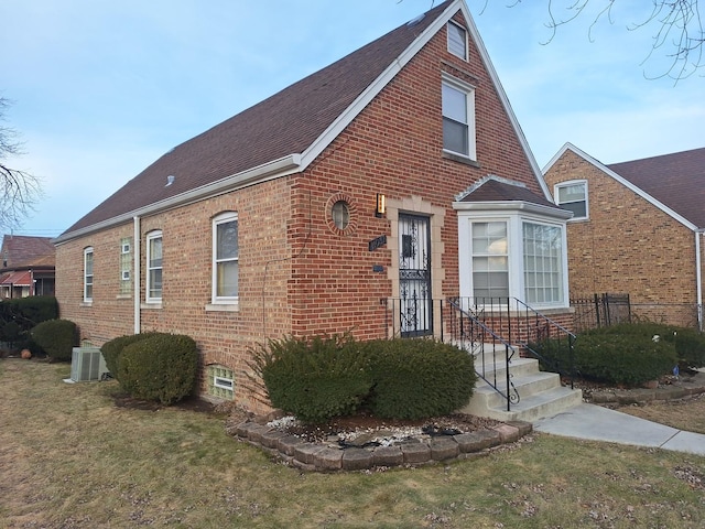 view of front of home with central AC and a front lawn