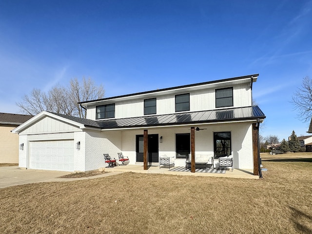 view of front of property with concrete driveway, an attached garage, a standing seam roof, a front lawn, and brick siding