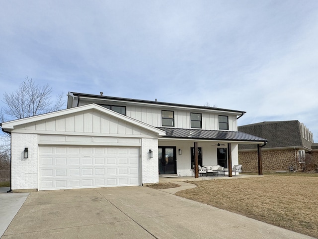 view of front facade featuring concrete driveway, an attached garage, a standing seam roof, covered porch, and brick siding