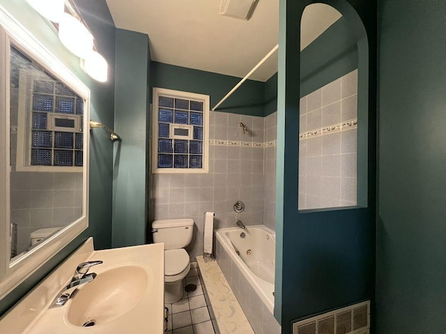 full bathroom with tile patterned flooring, tiled shower / bath, sink, and toilet