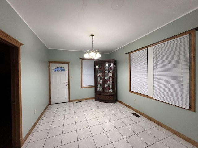 unfurnished dining area featuring ornamental molding, light tile patterned floors, and a notable chandelier