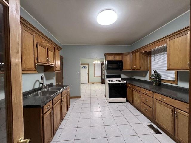 kitchen with sink, light tile patterned floors, a notable chandelier, and white gas stove