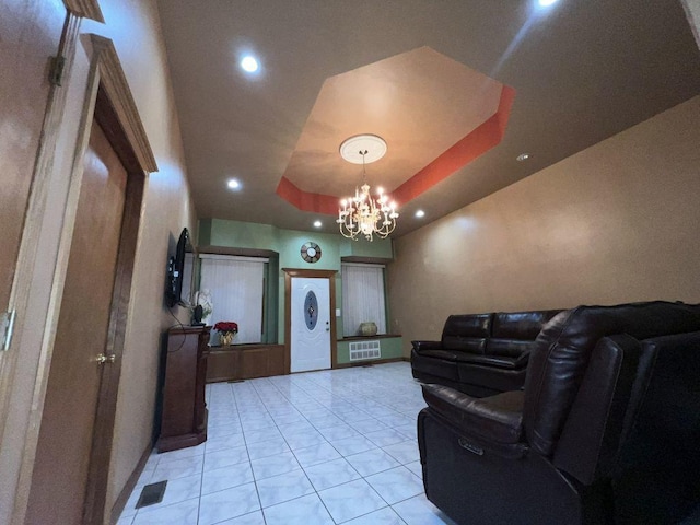 living room featuring a tray ceiling, a chandelier, and light tile patterned floors