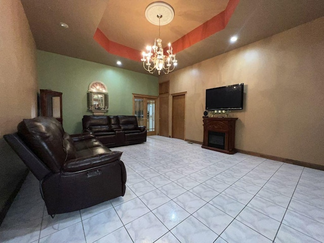 living room with a notable chandelier, a tray ceiling, and light tile patterned floors