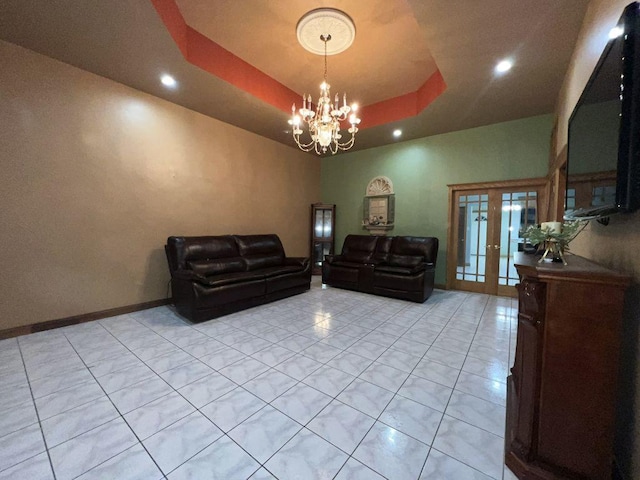 tiled living room featuring a raised ceiling, a chandelier, and french doors