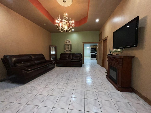 living room featuring an inviting chandelier, a tray ceiling, and light tile patterned floors