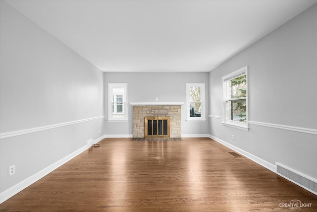 unfurnished living room featuring dark hardwood / wood-style floors and a stone fireplace