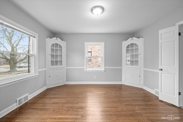 unfurnished room featuring dark wood-type flooring and a healthy amount of sunlight