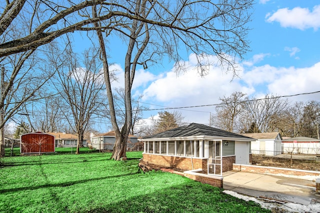 view of yard with a patio, concrete driveway, a sunroom, fence, and an outdoor structure