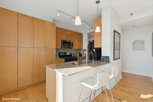 kitchen featuring pendant lighting, backsplash, a kitchen bar, gas range, and kitchen peninsula