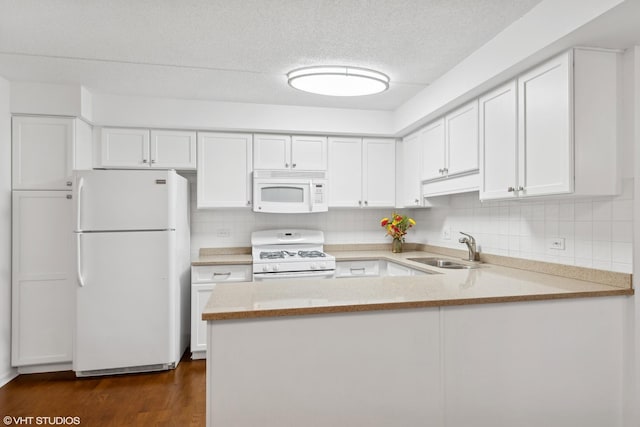 kitchen with white appliances, kitchen peninsula, sink, and white cabinets