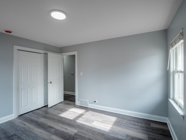 unfurnished bedroom featuring multiple windows, hardwood / wood-style floors, and a closet