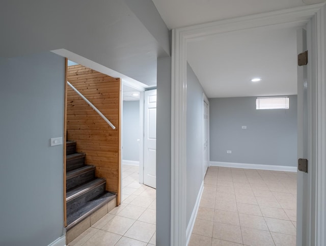 corridor featuring wooden walls and light tile patterned floors