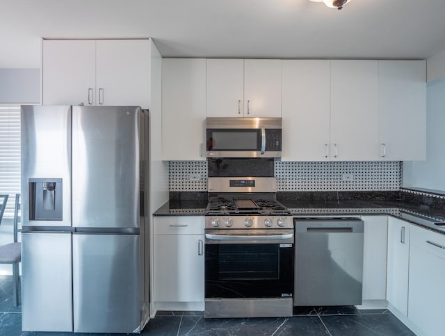 kitchen with dark stone countertops, decorative backsplash, white cabinets, and appliances with stainless steel finishes