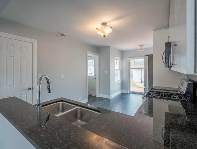 kitchen featuring sink, dark stone counters, kitchen peninsula, and appliances with stainless steel finishes