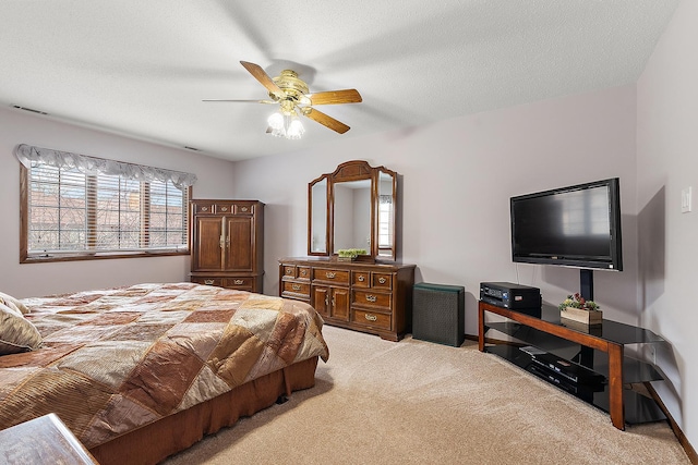 bedroom with ceiling fan, light colored carpet, and a textured ceiling