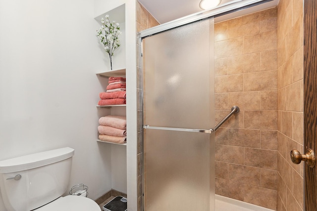 bathroom with a shower with shower door and toilet