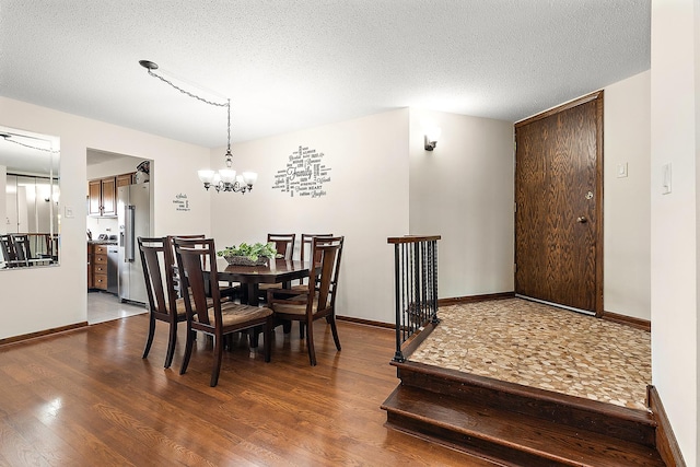 dining area featuring wood-type flooring, a notable chandelier, and a textured ceiling