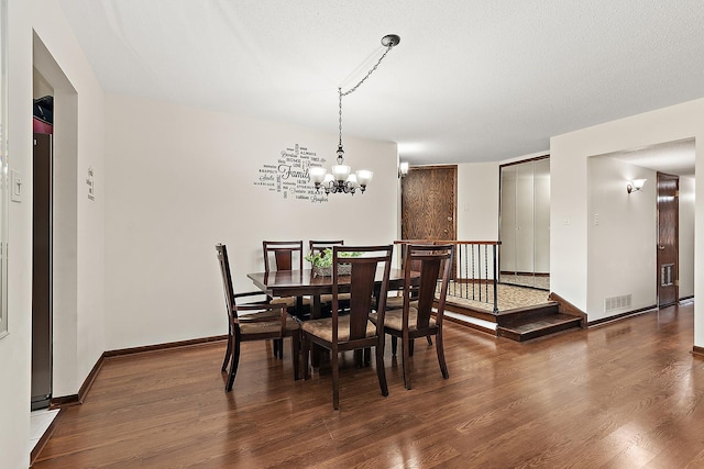 dining area with dark hardwood / wood-style flooring, a textured ceiling, and an inviting chandelier