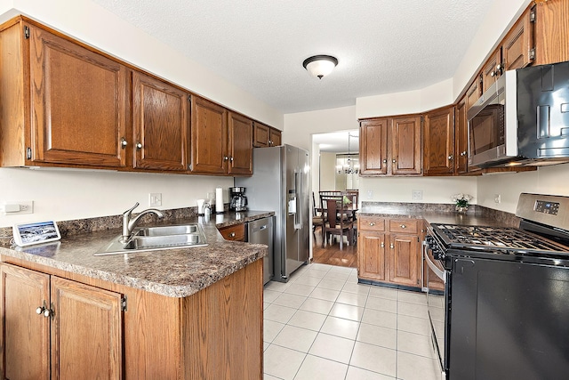 kitchen with light tile patterned flooring, appliances with stainless steel finishes, sink, kitchen peninsula, and a textured ceiling