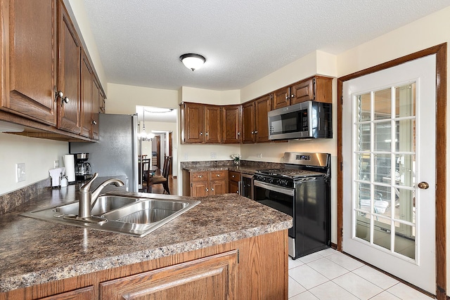 kitchen featuring sink, light tile patterned floors, stainless steel appliances, a textured ceiling, and kitchen peninsula