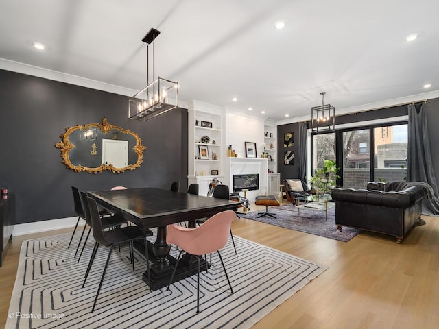 dining area with an inviting chandelier, built in features, light hardwood / wood-style flooring, and ornamental molding