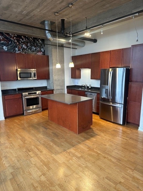 kitchen featuring stainless steel appliances, light wood-type flooring, hanging light fixtures, and a high ceiling