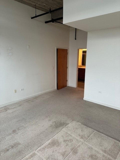 carpeted empty room featuring a towering ceiling