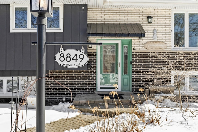 snow covered property entrance with brick siding