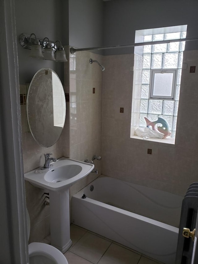 bathroom with tile patterned flooring, tiled shower / bath, and toilet