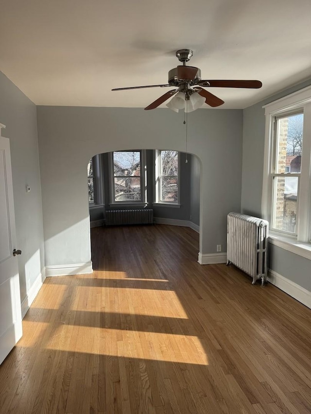 spare room with hardwood / wood-style floors, radiator heating unit, and ceiling fan