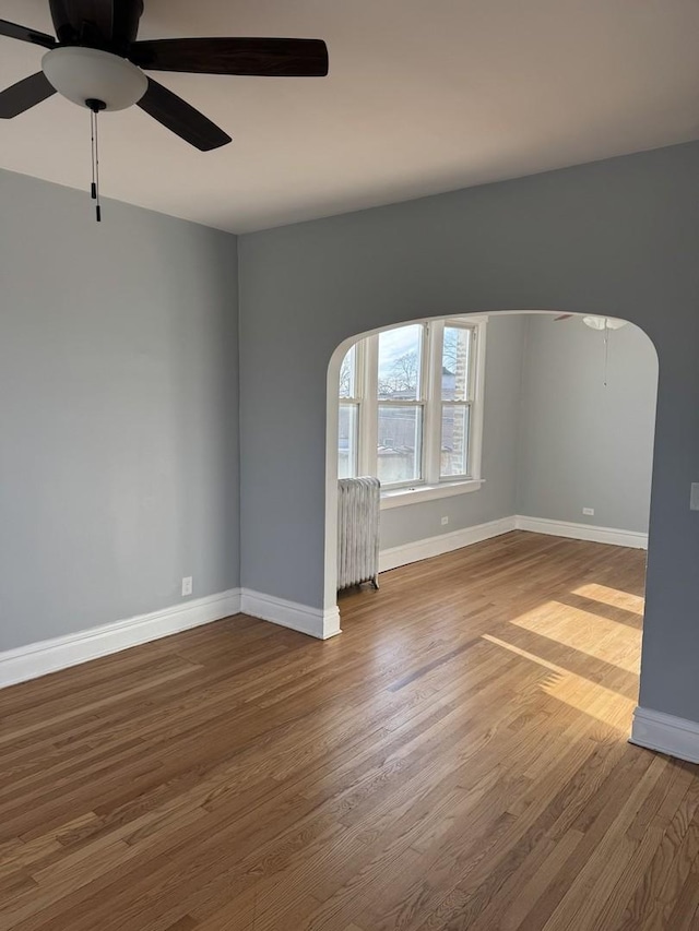 spare room with hardwood / wood-style flooring, radiator heating unit, and ceiling fan