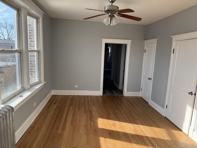 spare room with hardwood / wood-style floors, radiator heating unit, and ceiling fan