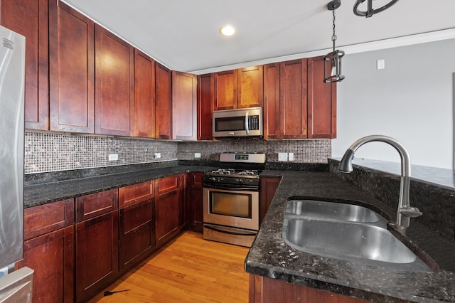 kitchen with dark stone countertops, hanging light fixtures, sink, and appliances with stainless steel finishes