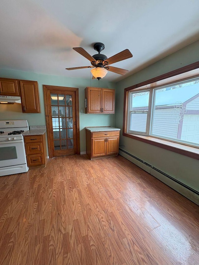 kitchen with ceiling fan, white gas range, a baseboard heating unit, and light hardwood / wood-style floors