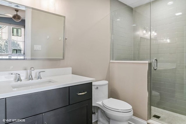 bathroom with ceiling fan, vanity, toilet, and an enclosed shower