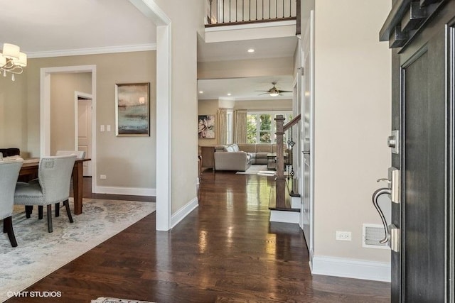 entrance foyer featuring dark wood-type flooring, ornamental molding, and an inviting chandelier